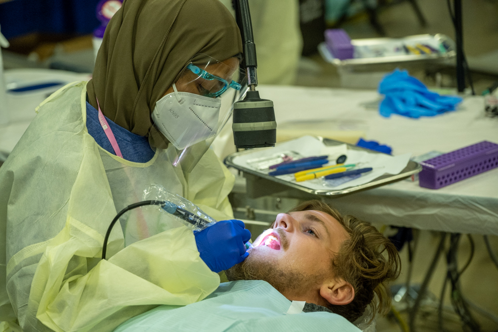 Dental hygienist cleans patient's teeth